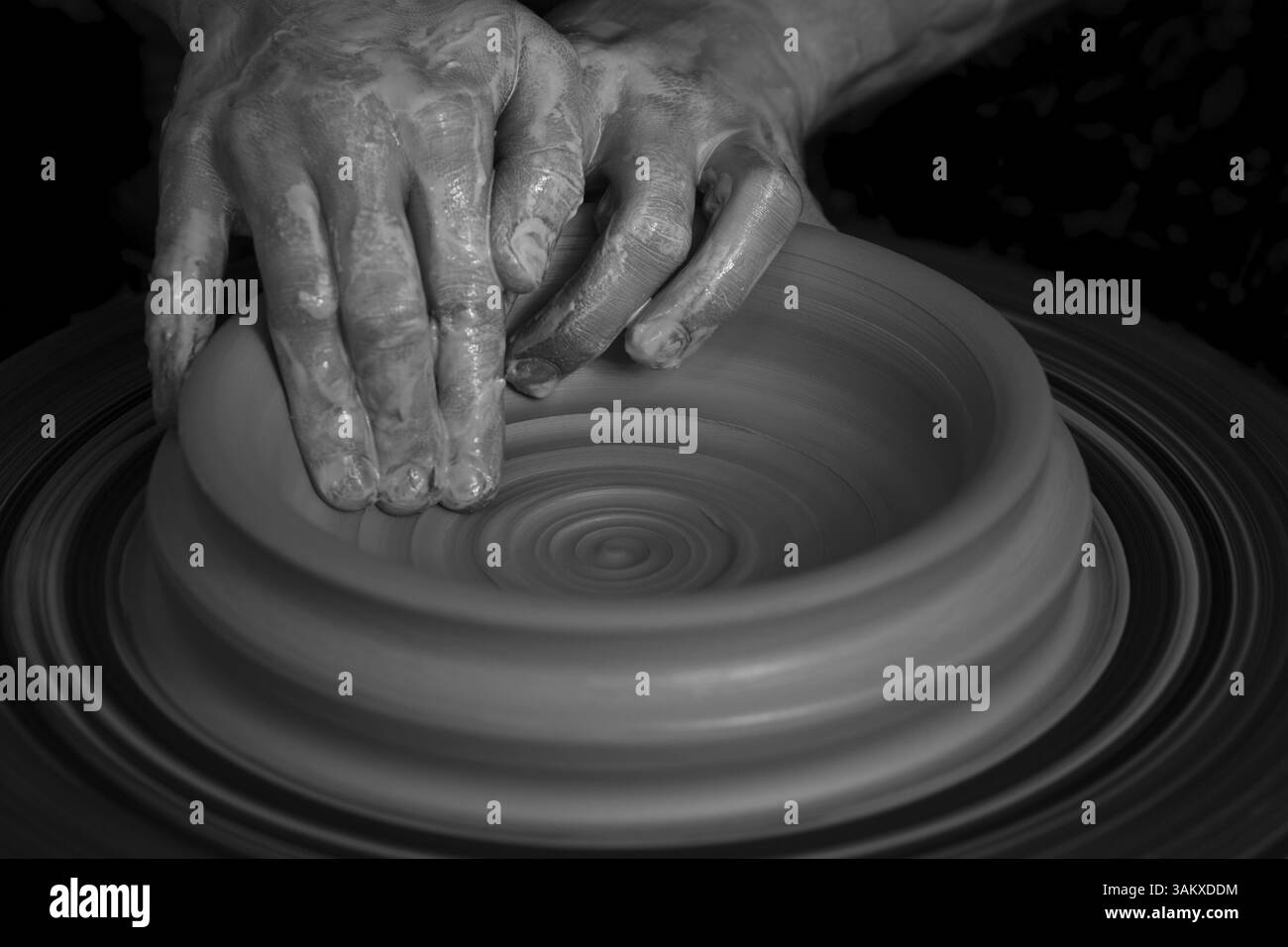 Mani che modellano una ciotola di argilla su un pannello di vasaio in un'immagine artistica in bianco e nero, ceramiche di Wiggensbach, Baviera, Germania, Europa Foto Stock