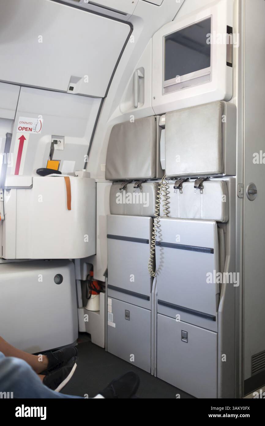 Sedili posteriori piegati per hostess con cinture di sicurezza e TV sopra la parte anteriore del moderno aereo passeggeri Foto Stock