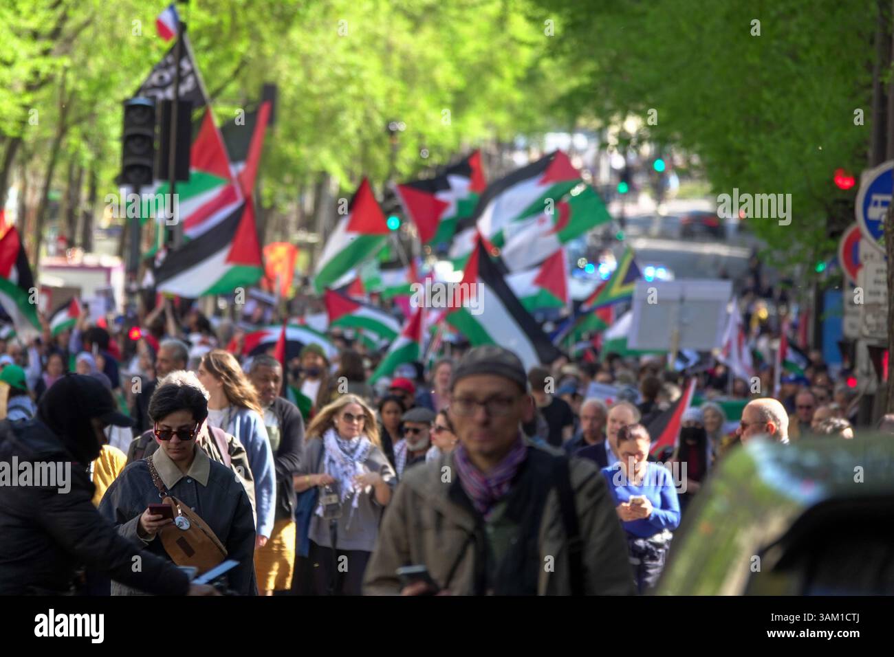 Folla di manifestanti in marcia a Parigi, durante una manifestazione pro-Palestina. I partecipanti ondeggiano bandiere e striscioni palestinesi a sostegno di Gaza Foto Stock