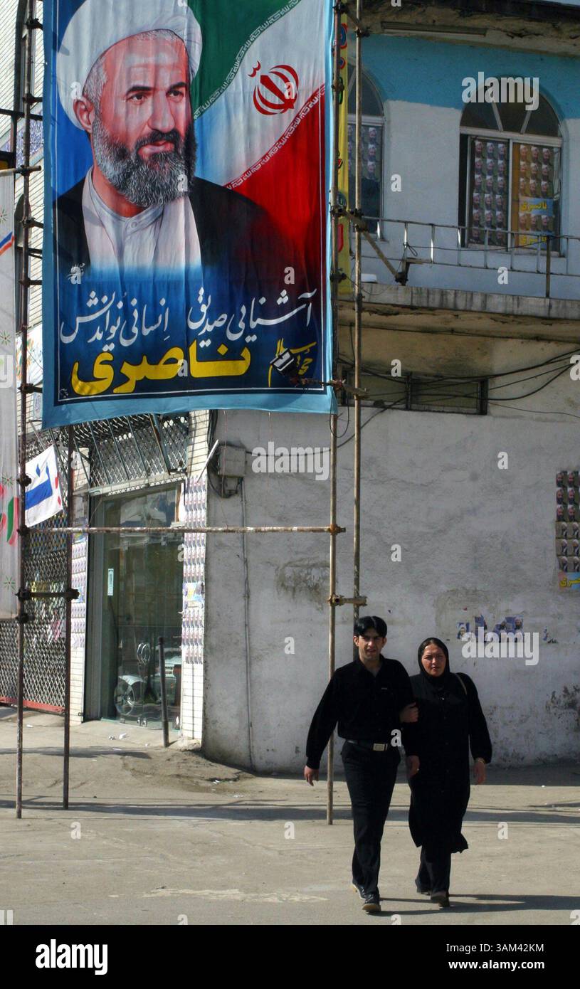 19 febbraio 2004 - Stati Uniti - KRT WORLD NEWS STORY SLUGGED: IRAN-POLITICS KRT PHOTOGRAPH BY FARZANEH KHADEMIAN/KRT (19 febbraio) BABOL, IRAN-- Una giovane coppia iraniana cammina sotto una campagna di un candidato conservatore della città di Babol nel nord di Teheran, 19 febbraio 2004. L'apatia degli elettori è dilagante anche a Babol, dove ci sono 34 candidati in tutto lo spettro politico che lottano per due seggi. (lde) 2004 (immagine di credito: © Farzaneh Khademian/mct/ZUMAPRESS.com) Foto Stock