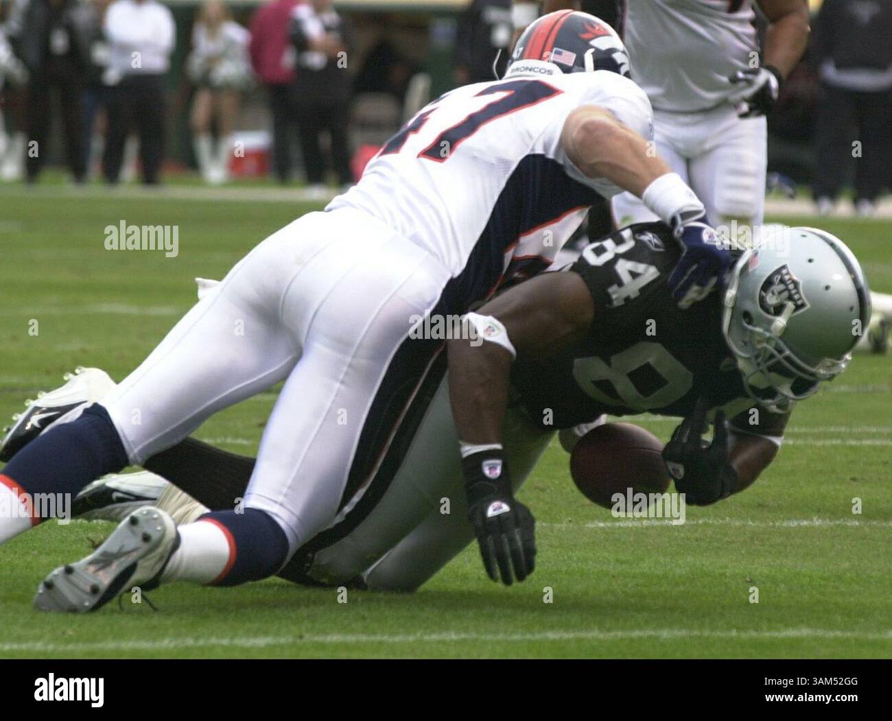 17 ottobre 2004 - U.S. - KRT SPORTS STORY SLUGGED: BRONCOS-RAIDERS KRT PHOTOGRAPH BY EDDIE LEDESMA/CONTRA COSTA TIMES (17 ottobre) OAKLAND, CA -- il wide receiver dei Raiders Jerry Porter fumò la palla mentre fu placcato da John Lynch dei Broncos nel secondo quarto della loro partita al Network Associates Coliseum di Oakland, California, domenica 17 ottobre 2004. (Mvw) 2004 (immagine di credito: © Eddie Ledesma/mct/ZUMAPRESS.com) Foto Stock