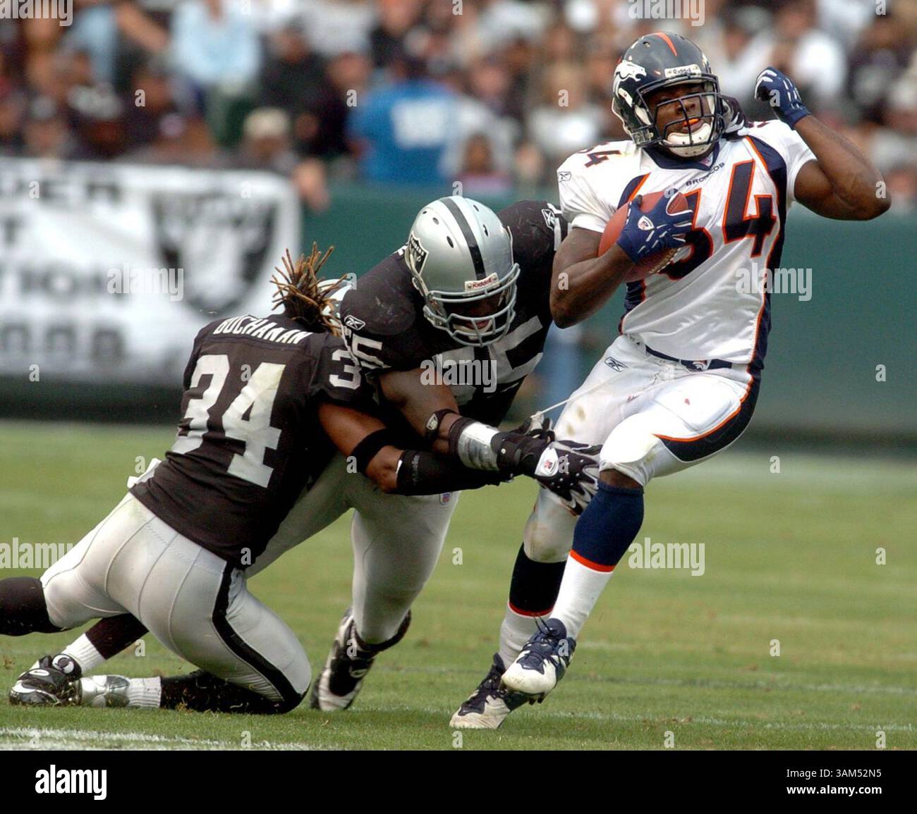 17 ottobre 2004 - Stati Uniti - KRT SPORTS STORY SLUGGED: BRONCOS-RAIDERS KRT PHOTOGRAPHY DI DAN HONDA/CONTRA COSTA TIMES (17 ottobre) OAKLAND, CA -- OAKLAND's Ray Buchanan, Left, e Danny Clark cercano di fermare i Reuben Droughns di Denver durante la loro partita al Network Associates Coliseum di Oakland, California, domenica 17 ottobre 2004. (Mvw) 2004 (immagine di credito: © Dan Honda/mct/ZUMAPRESS.com) Foto Stock