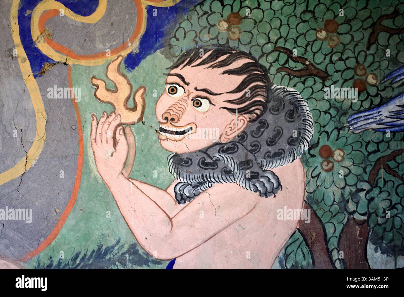 Spirito sorridente che tiene una fiamma sotto un albero fiorito nel murale del monastero di Thiksey, Ladakh. Foto Stock