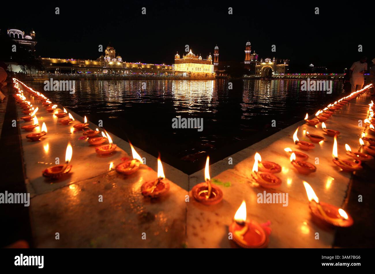 Le celebrazioni del festival Baisakhi al Tempio d'Oro, le lampade a olio dell'India sono illuminate dai devoti come segno di celebrazione e devozione al Tempio d'Oro appositamente illuminato, il luogo più sacro dei Sikh in occasione del festival Visakhi o Baisakhi ad Amritsar, India, il 13 aprile 2025. Nel 1699 d.C., Guru Gobind Singh Ji, il decimo Guru Sikh, istituì il Panth Khalsa, unendo i Sikh sotto un unico ordine. Questo evento importante viene commemorato durante il festival Visakhi, che segna anche l'inizio del capodanno Sikh. L'occasione è celebrata con grande devozione religiosa ed enthusi Foto Stock