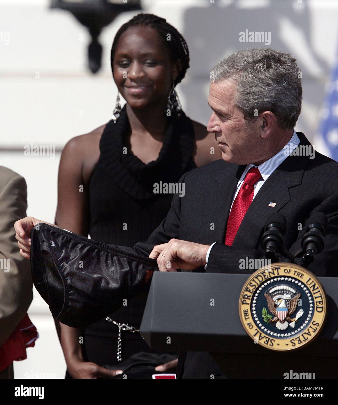 6 aprile 2006 - U.S. - la giocatrice di basket femminile dell'Università del Maryland Crystal Langhorne guarda come presidente George W. Bush viene presentato con un costume da bagno dalla squadra di Auburn Swim mentre si congratula con 12 squadre della National Collegiate Athletic Association (NCAA) per aver vinto titoli nazionali durante le stagioni 2005 e 2006 sul South Lawn della Casa Bianca a Washington, DC giovedì 6 aprile 2006. (Chuck Kennedy/KRT) (immagine di credito: © Chuck Kennedy/mct/ZUMAPRESS.com) Foto Stock