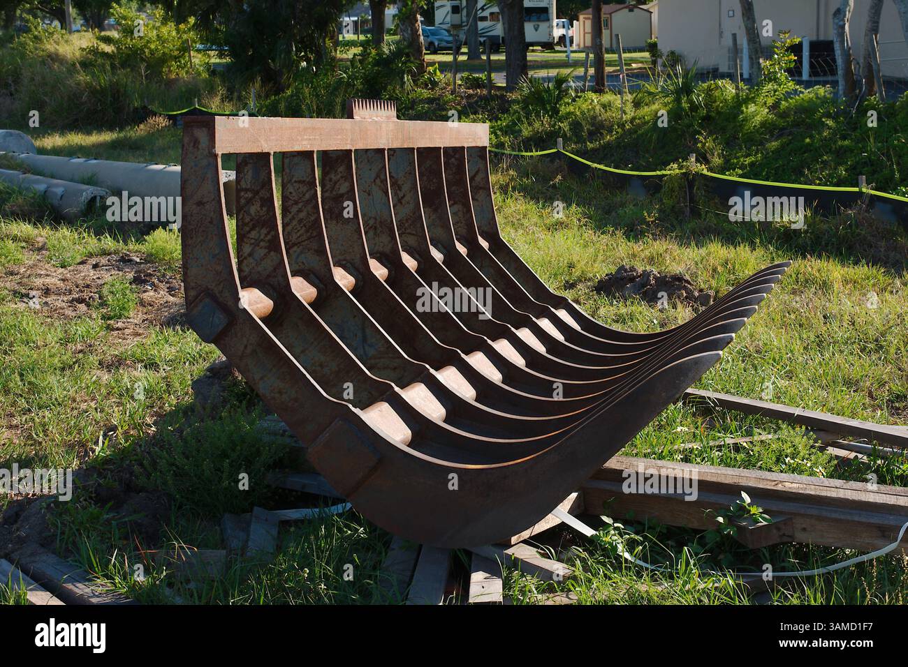 Struttura rustica in metallo per rastrello a radice in un ambiente da costruzione all'aperto circondato da vegetazione. Struttura metallica arrugginita e resistente agli agenti atmosferici all'aperto Foto Stock
