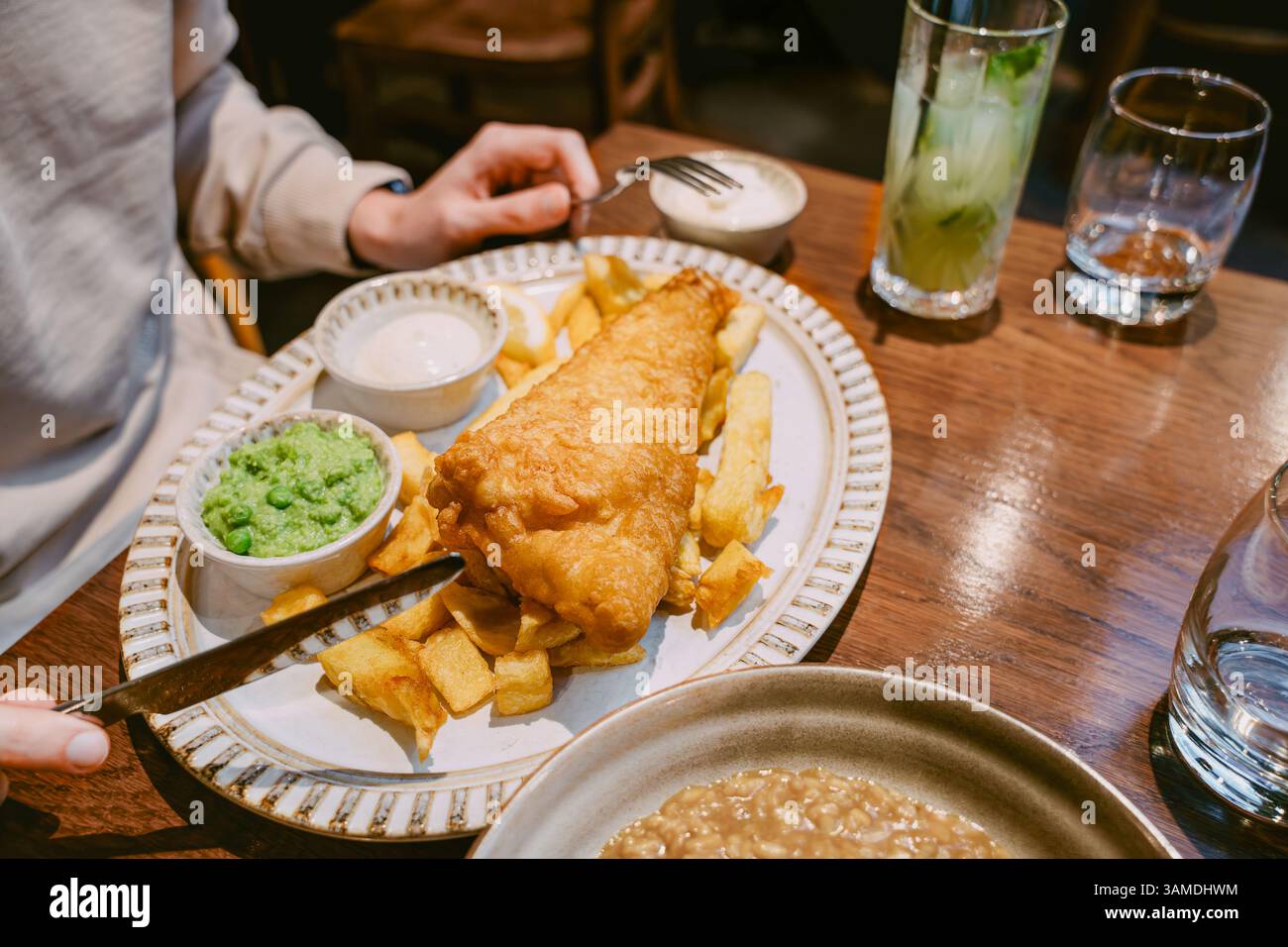 Pesce tradizionale e patatine fritte servite con salsa di tartaro di piselli moschi su un piatto in un tavolo del ristorante Foto Stock