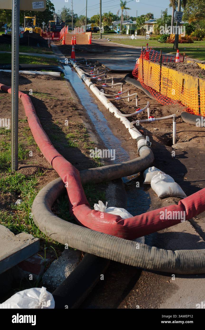 Strade in costruzione con barriere di sicurezza, tubi dell'acqua bianca temporanei e sistema di drenaggio. Tubi di drenaggio, coni di avvertenza e attrezzature che garantiscono Foto Stock