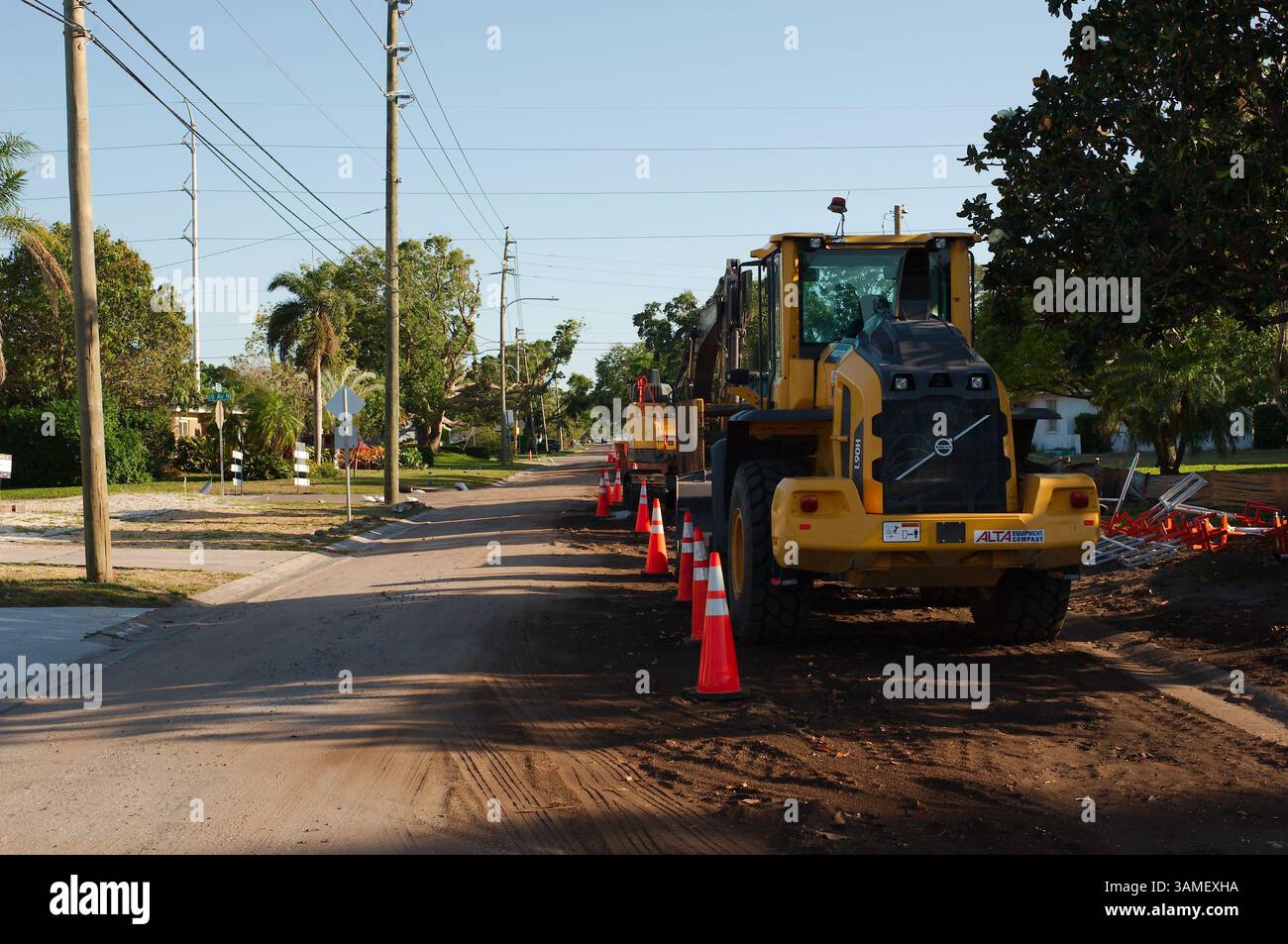 Costruzione di strade sito di riparazione di trincee con barriere arancioni e coni di sicurezza durante il giorno. Cantiere con escavatori, barriere di sicurezza arancioni, Foto Stock