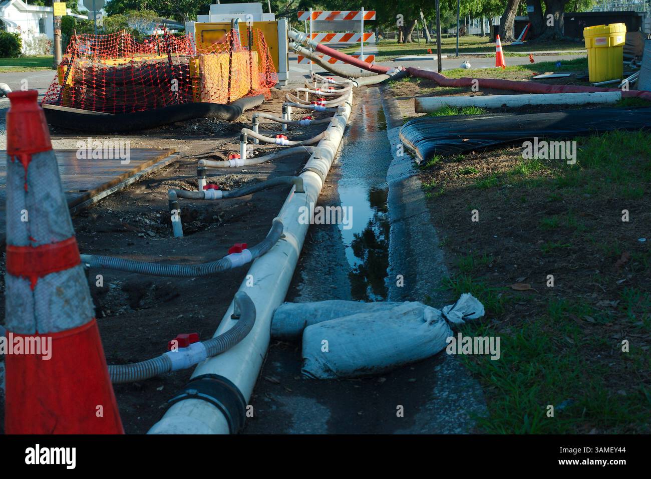 Strade in costruzione con barriere di sicurezza, tubi dell'acqua bianca temporanei e sistema di drenaggio. Tubi di drenaggio, coni di avvertenza e attrezzature che garantiscono Foto Stock