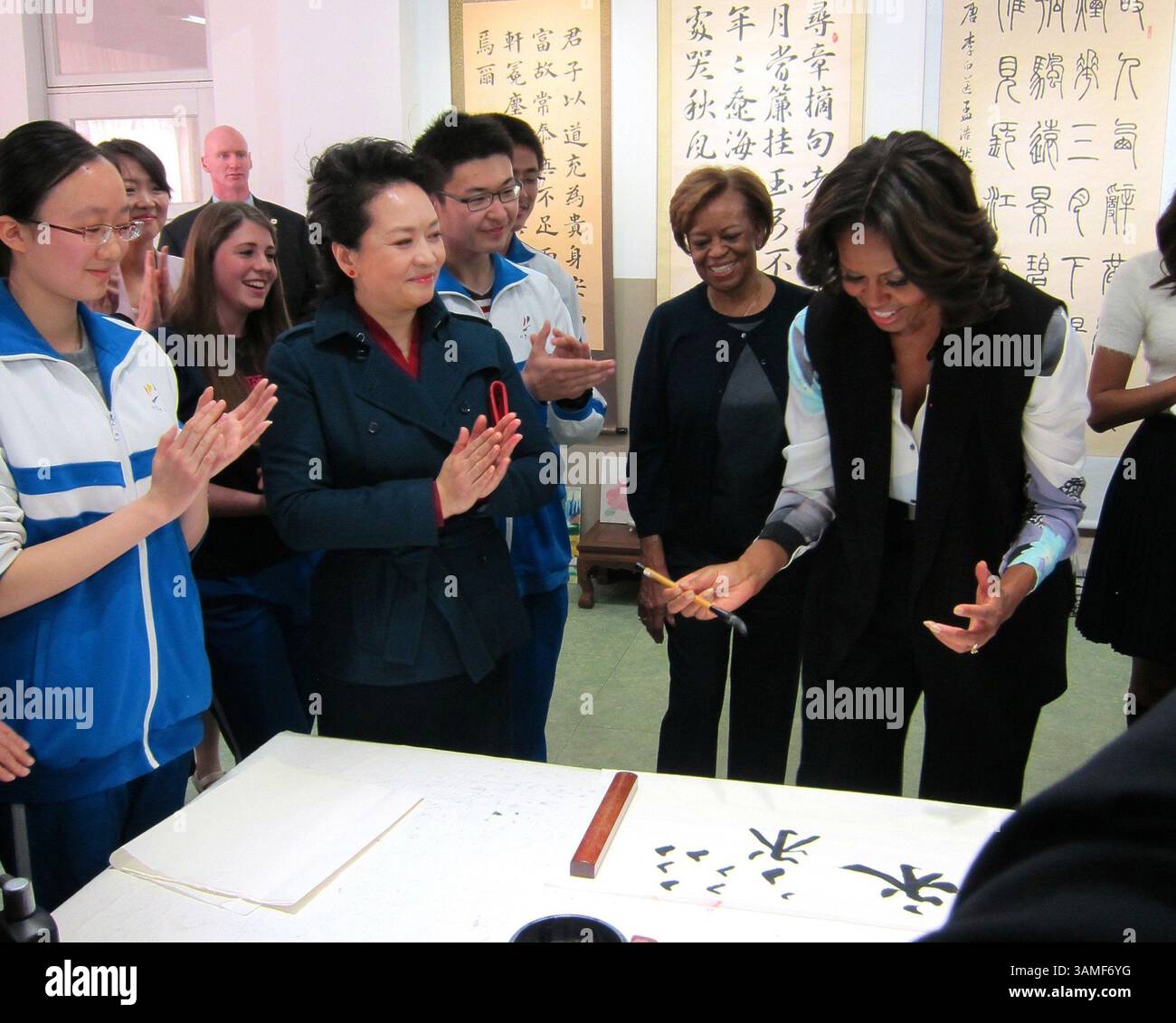 21 marzo 2014 - Pechino, CHN - la first lady Michelle Obama tenta di scrivere il carattere cinese per "eterno" o "per sempre", un compito difficile, dato che coinvolge tutti e otto i colpi di base della calligrafia cinese. È con Peng Liyuan, moglie del presidente cinese Xi Jinping, e studenti della Beijing Normal School di Pechino. All'estrema destra c'è Liu Yijie, 17 anni, che ha detto nella mia storia: "La signora Obama ha tenuto il suo pennello molto bene". Venerdì 21 marzo 2014. (Immagine di credito: © Stuart Leavenworth/MCT/ZUMAPRESS.com) Foto Stock