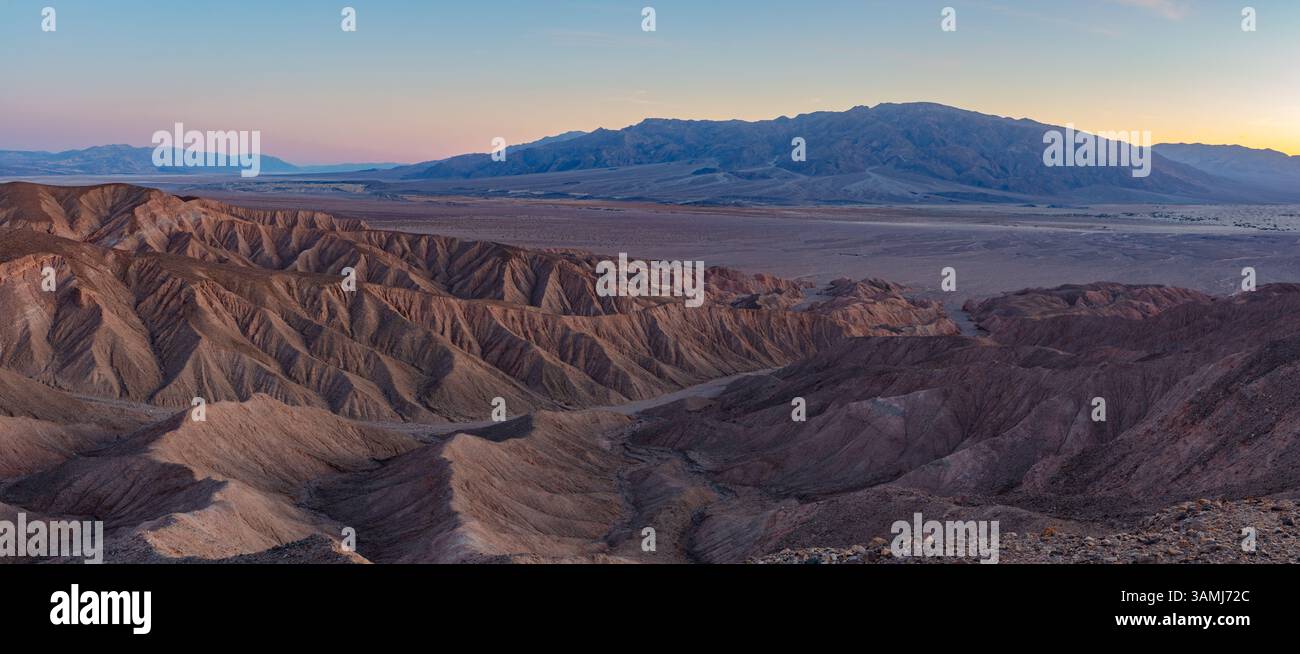 Calanchi deserti erosi del Death Valley National Park al tramonto. Le montagne Tucki si innalzano sopra le dune di sabbia di Mesquite Flat in questa colorata serata. Foto Stock