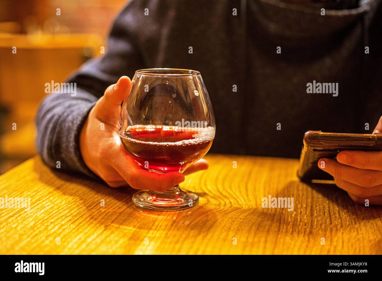 bevi un tè alla frutta e guardalo sullo smartphone. Pausa Foto Stock