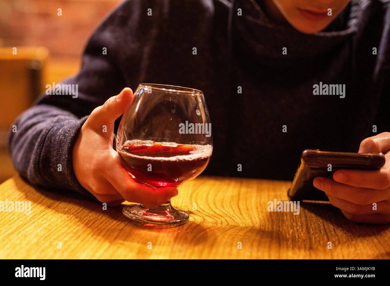 bevi un tè alla frutta e guardalo sullo smartphone. Pausa Foto Stock
