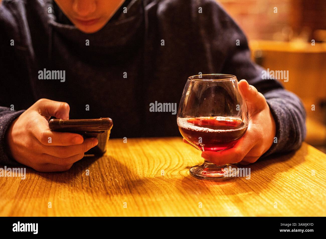 bevi un tè alla frutta e guardalo sullo smartphone. Pausa Foto Stock