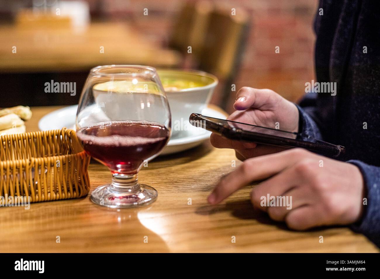bevi il tè alla frutta da un bicchiere e guardalo su uno smartphone Foto Stock