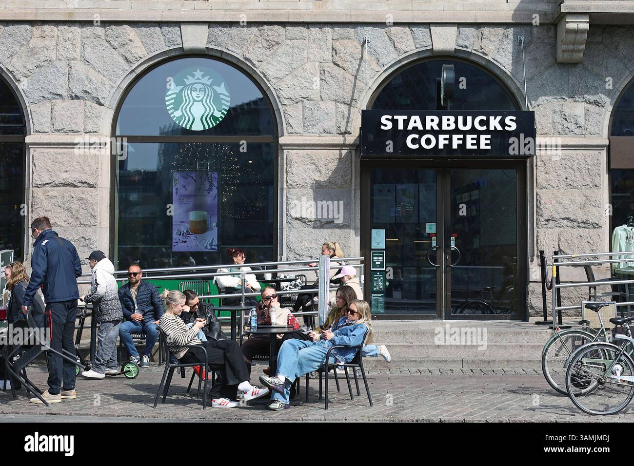 Persone sedute di fronte a un coffee store Starbucks in Copenhagen City Hall Square (Rådhuspladsen) Foto Stock