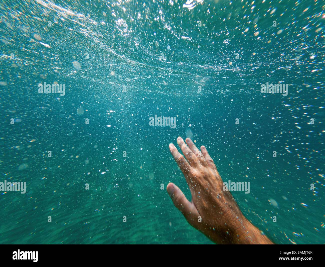 Annegamento che solleva la mano attraverso le acque profonde dell'oceano per chiedere aiuto e assistenza, riprese subacquee, messa a fuoco selettiva Foto Stock