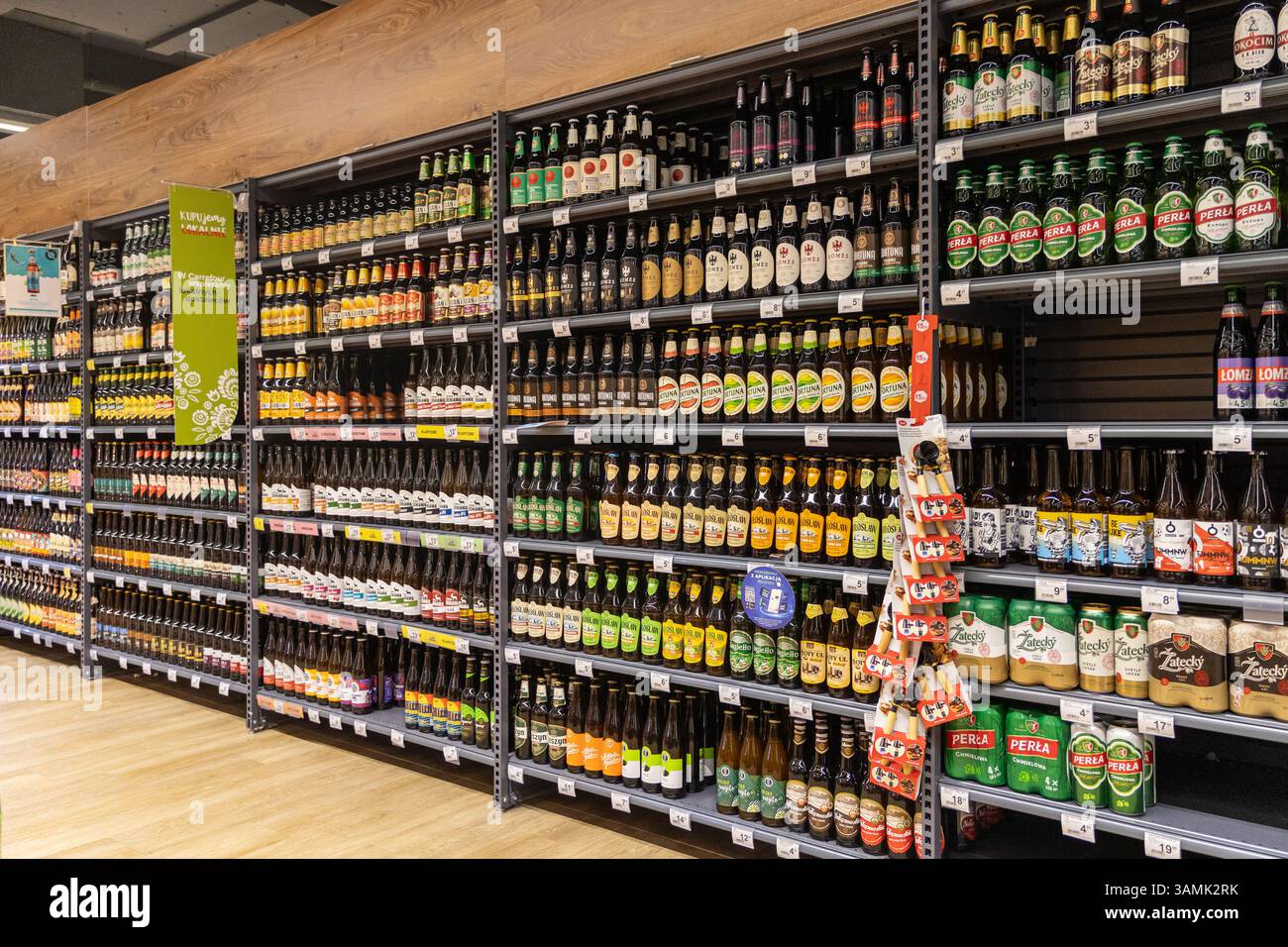Poznan, Polonia - 8 aprile 2025: Primo piano di una mano che raccoglie una bottiglia di sidro di mora di Somersby da uno scaffale del negozio tra varie bevande aromatizzate, berretto Foto Stock