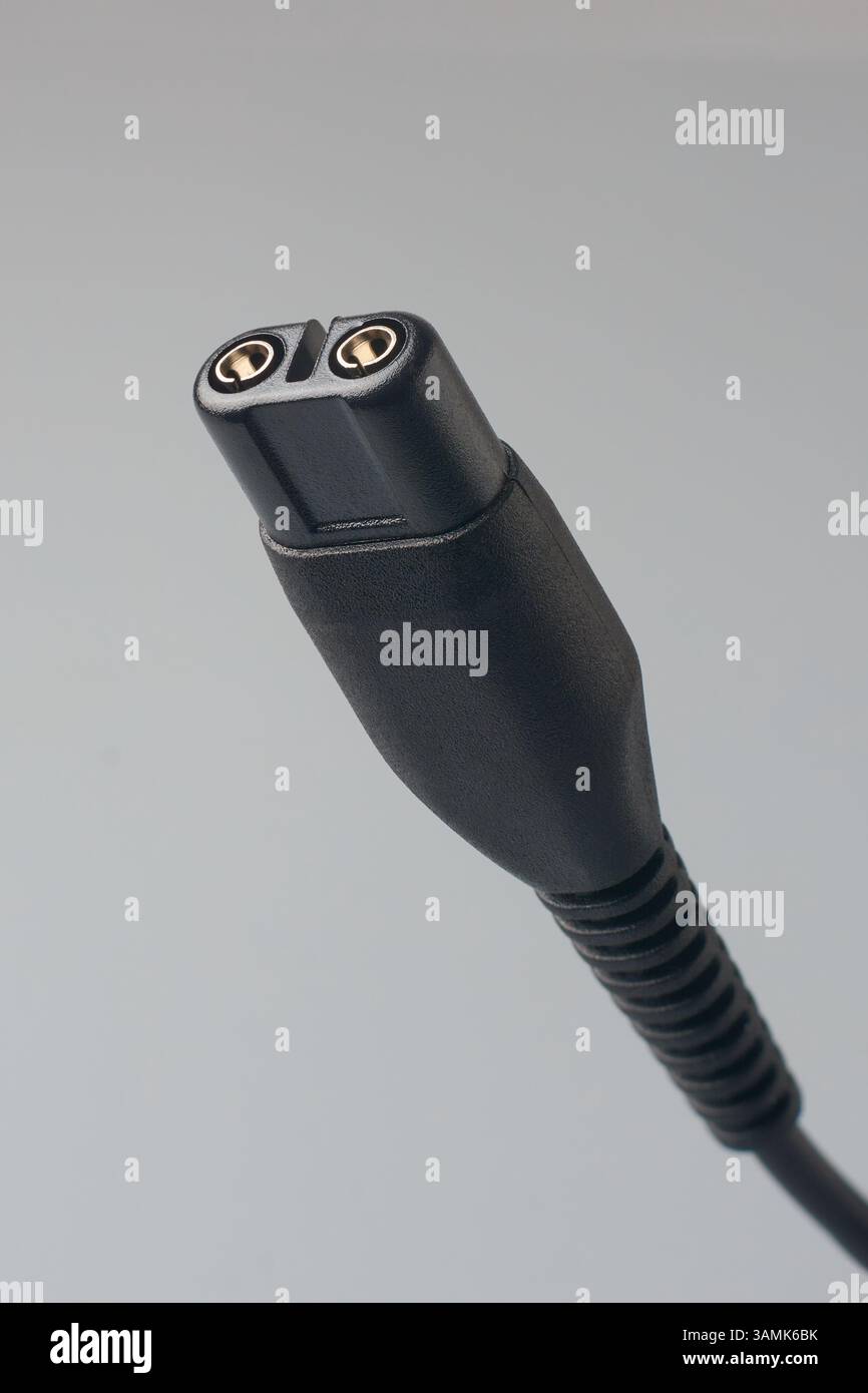 primo piano della spina elettrica nera o del connettore di carica del dispositivo elettronico sfondo grigio isolato, con due contatti metallici circolari nella parte superiore Foto Stock
