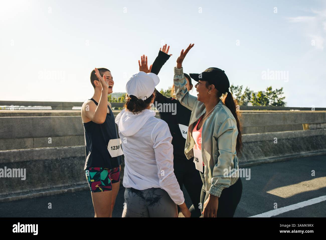 Un gruppo di donne podiste felici festeggiano la loro partecipazione di successo alla gara con alti premi. Sono all'aperto in una giornata di sole, dando prova di un senso di Foto Stock