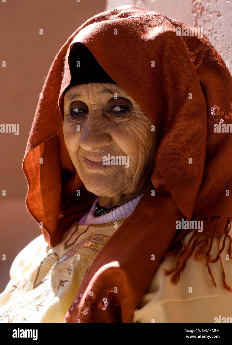 Una donna anziana siede in una prospettiva nella Valle del Dades in Marocco. (retroilluminato) Foto Stock