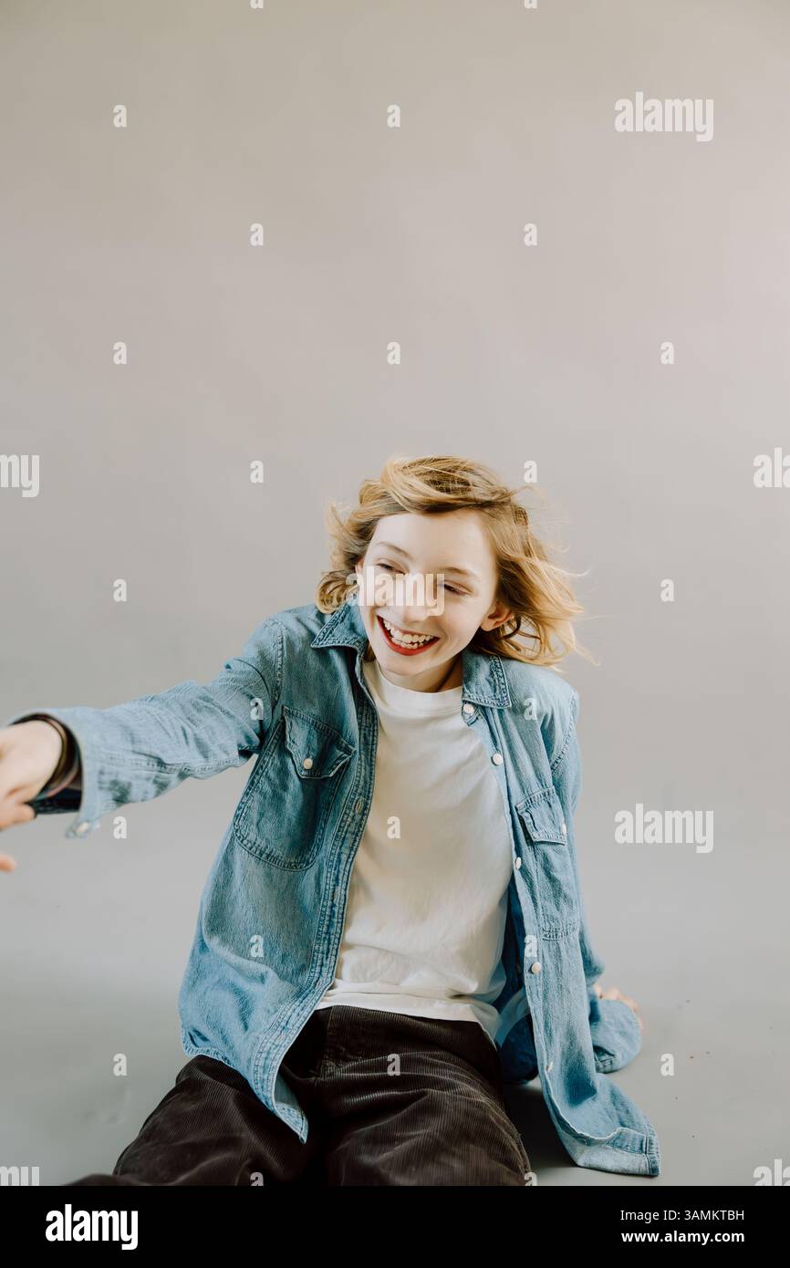 Il ragazzo si inclina in avanti con il braccio allungato e un sorriso giocoso Foto Stock