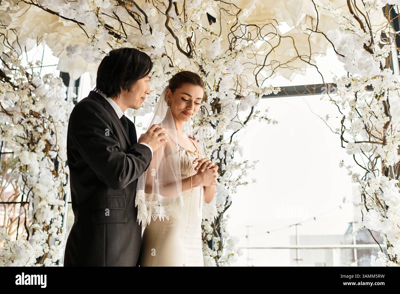 Una coppia gioiosa si scambia i voti circondati da splendide decorazioni floreali, che mostrano il loro amore. Foto Stock