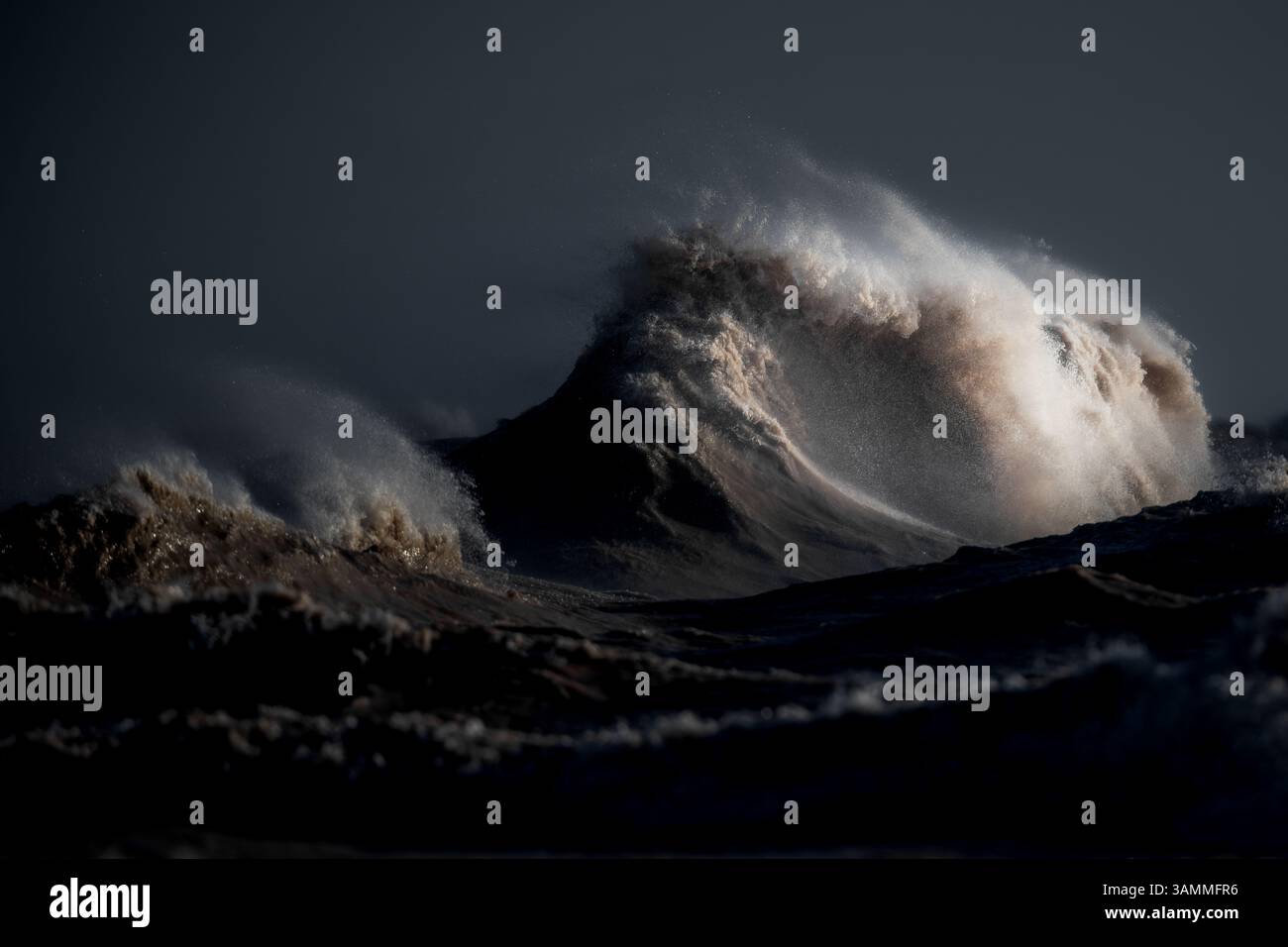 Immagine a colori del paesaggio costiero che mostra le onde, frustate da forti venti fino al punto in cui sembrano esplodere dall'acqua. Foto Stock
