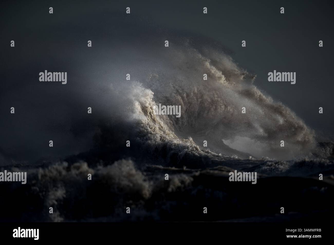 Immagine a colori del paesaggio costiero che mostra le onde, frustate da forti venti fino al punto in cui sembrano esplodere dall'acqua. Foto Stock