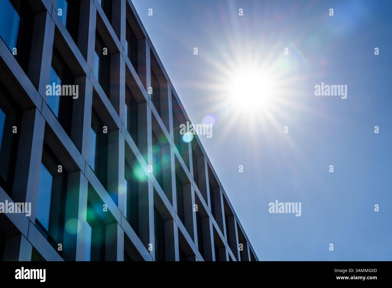 Edificio di uffici contemporaneo sotto il sole, che presenta una griglia strutturata di finestre in vetro e linee architettoniche pulite Foto Stock