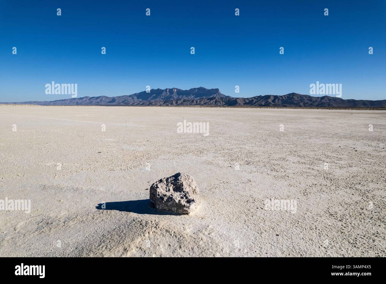 Vista aerea delle saline con una roccia su un letto di sale e delle montagne Guadalupe sullo sfondo, Salt Flat, Texas, Stati Uniti. Foto Stock