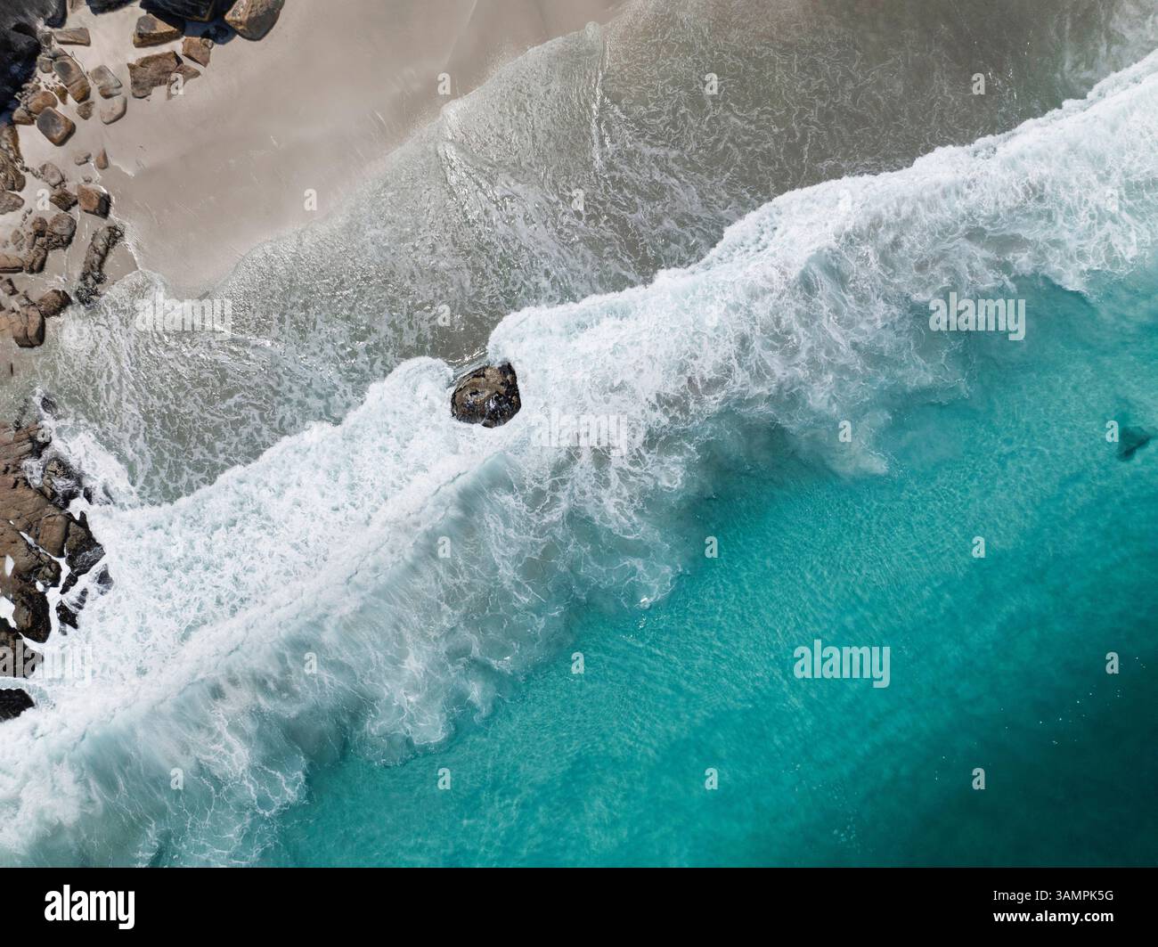 Vista aerea di una splendida spiaggia con acque cristalline e onde che si infrangono sulle rocce, Camps Bay, Western Cape, Sud Africa. Foto Stock
