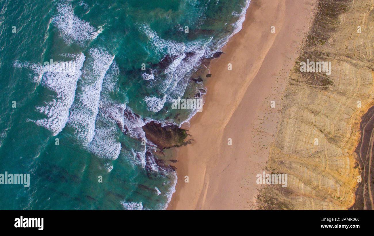 Vista aerea delle scogliere rocciose costiere e delle onde oceaniche al tramonto Foto Stock