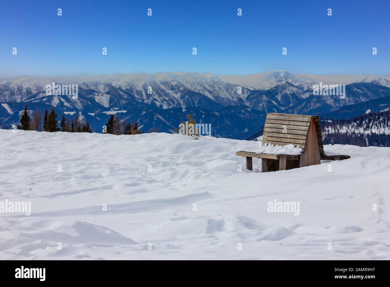 Panca innevata nella maestosa scena alpina Foto Stock