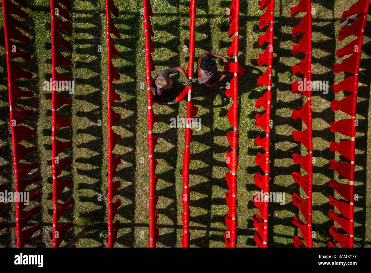 Veduta aerea di persone che lavorano appese panni rossi colorati ai fili per asciugare a Narayanganj, Bangladesh. Foto Stock