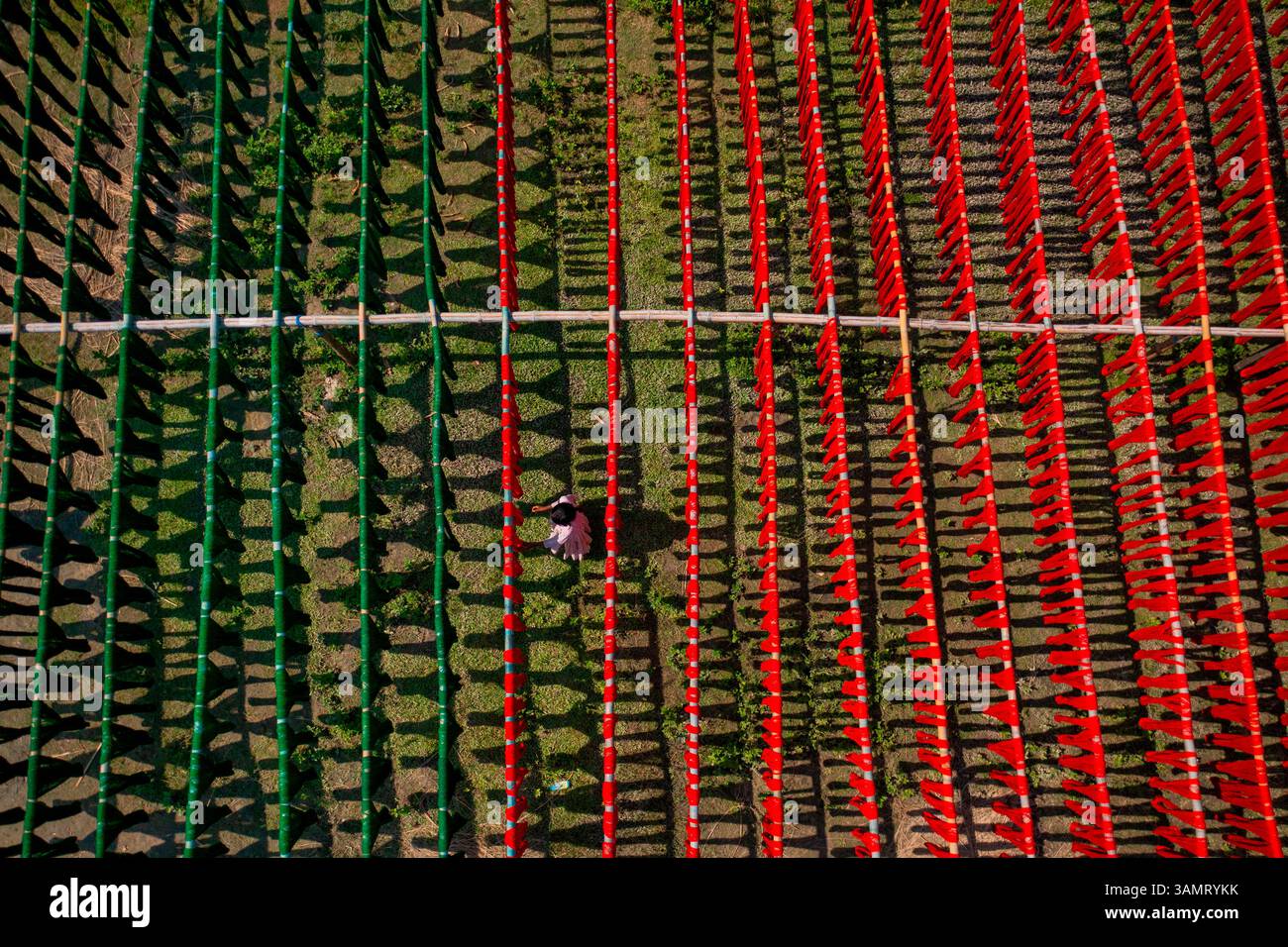 Veduta aerea di persone che lavorano appese panni rossi colorati ai fili per asciugare a Narayanganj, Bangladesh. Foto Stock