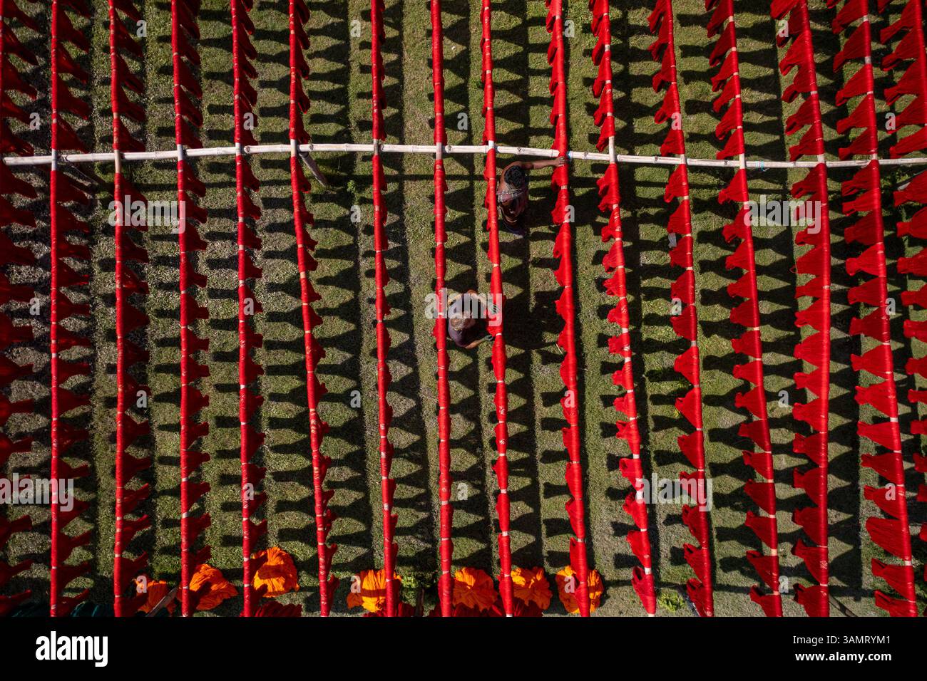 Veduta aerea di persone che lavorano appese panni rossi colorati ai fili per asciugare a Narayanganj, Bangladesh. Foto Stock