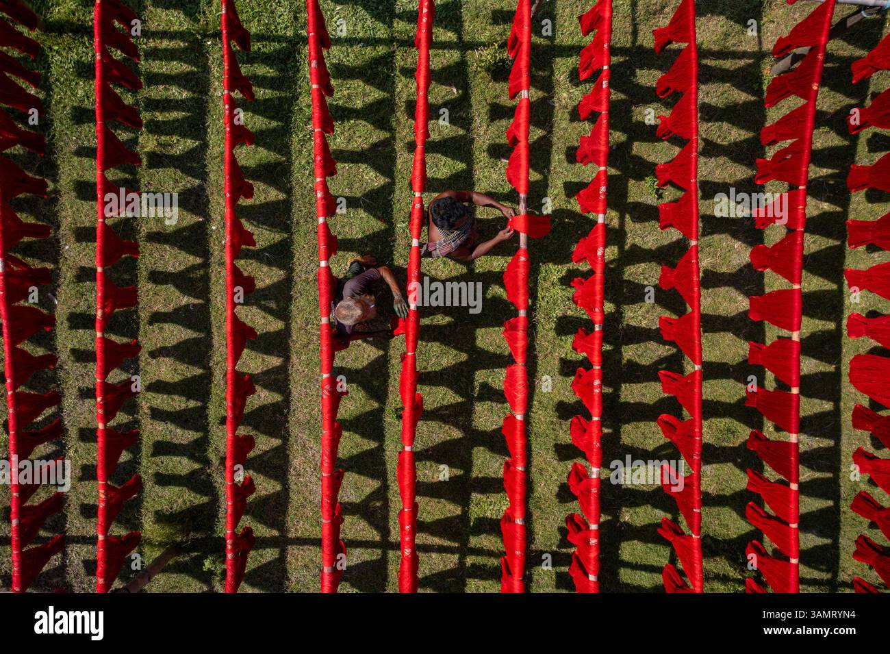 Veduta aerea di persone che lavorano appese panni rossi colorati ai fili per asciugare a Narayanganj, Bangladesh. Foto Stock