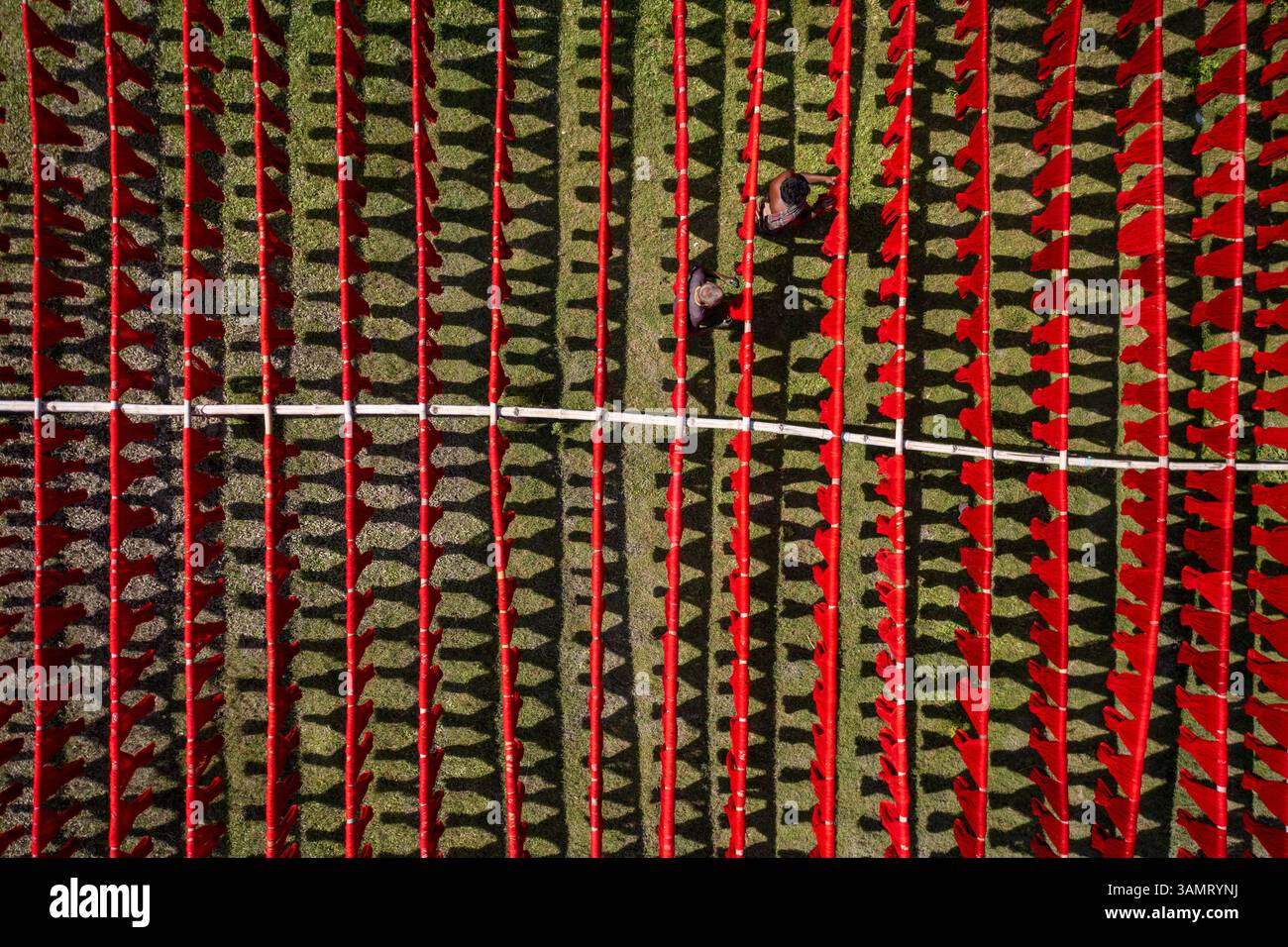 Veduta aerea di persone che lavorano appese panni rossi colorati ai fili per asciugare a Narayanganj, Bangladesh. Foto Stock