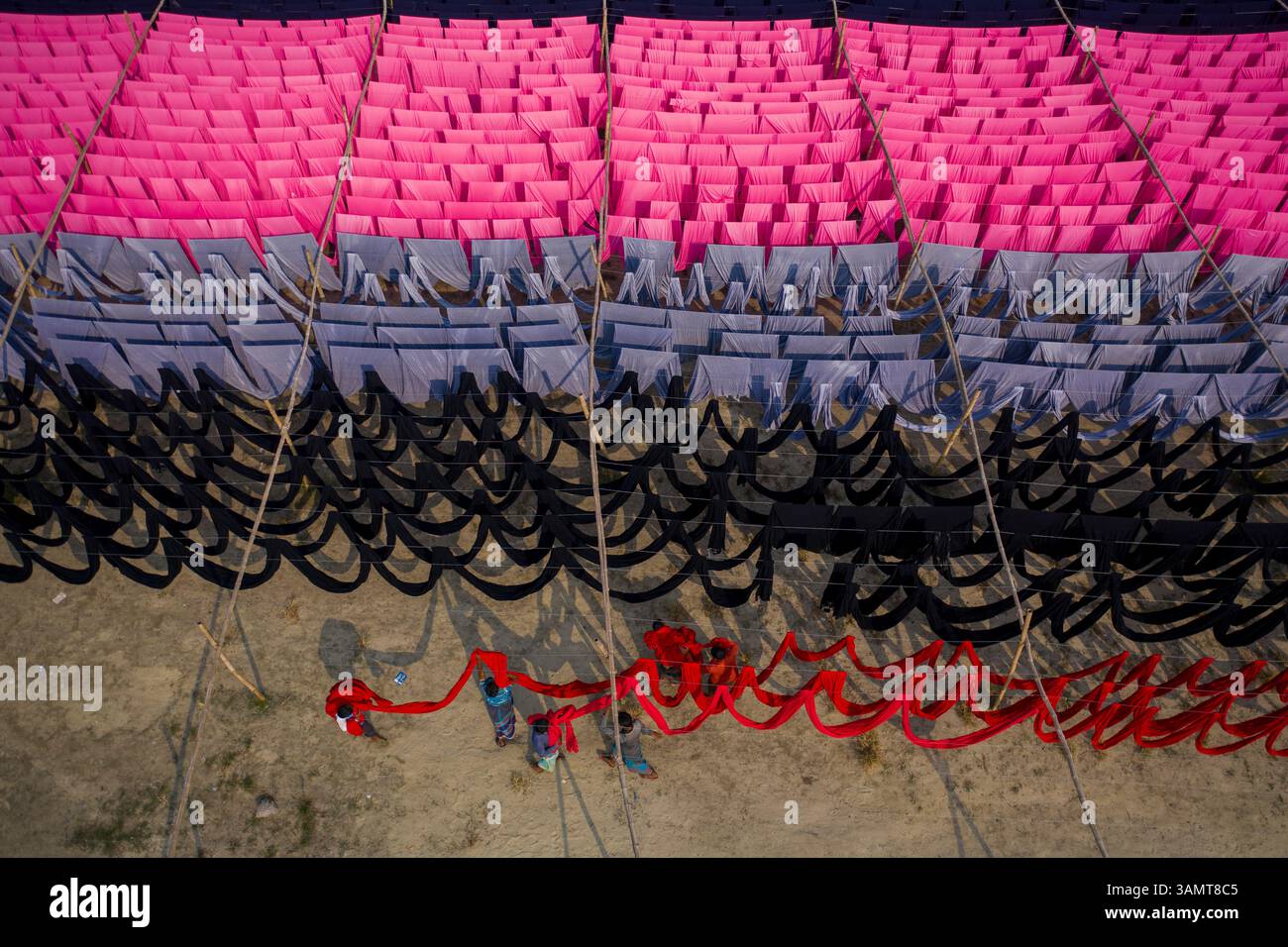 Veduta aerea di lavoratori che pendono migliaia di metri di diversi tessuti colorati per magliette da asciugare a Narayanganj, Dhaka, Bangladesh. Foto Stock