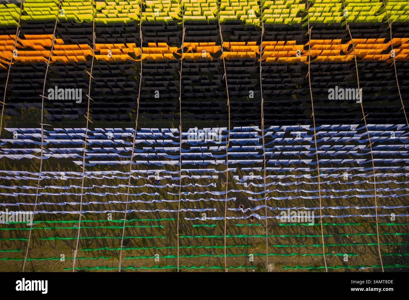 Veduta aerea di lavoratori che pendono migliaia di metri di diversi tessuti colorati per magliette da asciugare a Narayanganj, Dhaka, Bangladesh. Foto Stock