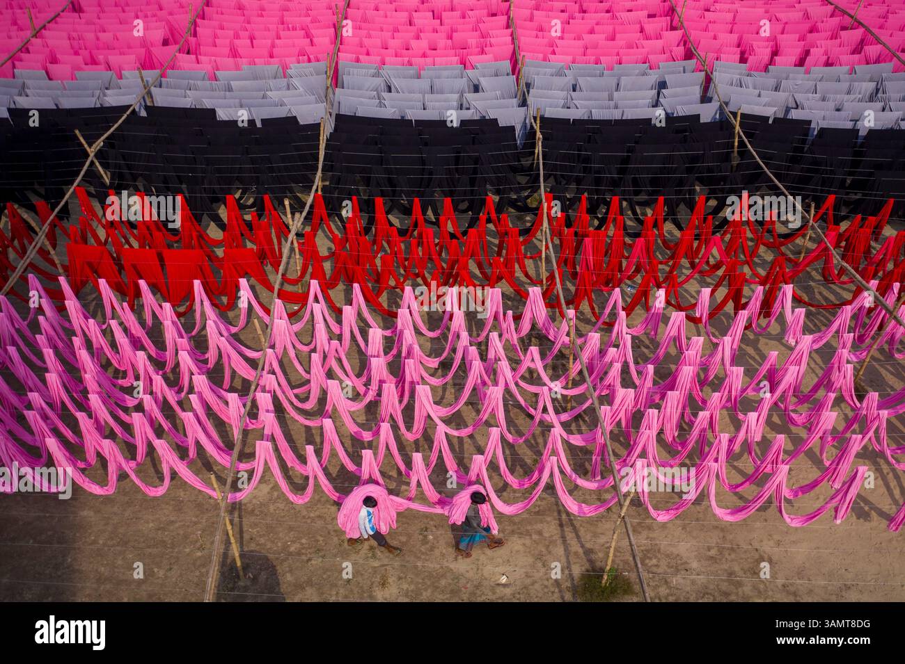 Veduta aerea di lavoratori che pendono migliaia di metri di diversi tessuti colorati per magliette da asciugare a Narayanganj, Dhaka, Bangladesh. Foto Stock