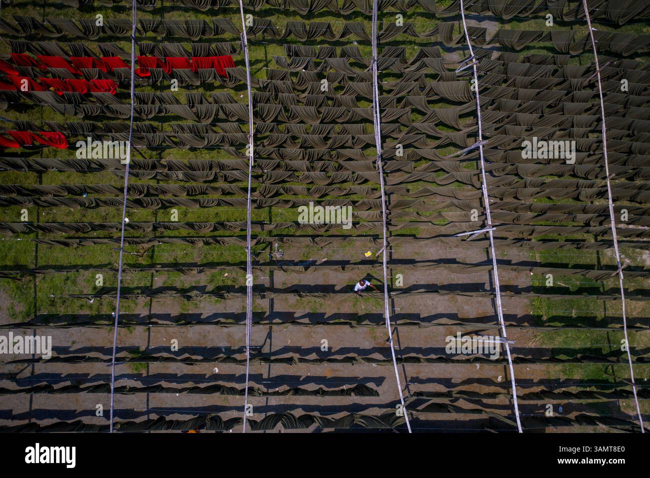 Veduta aerea di lavoratori che pendono migliaia di metri di diversi tessuti colorati per magliette da asciugare a Narayanganj, Dhaka, Bangladesh. Foto Stock
