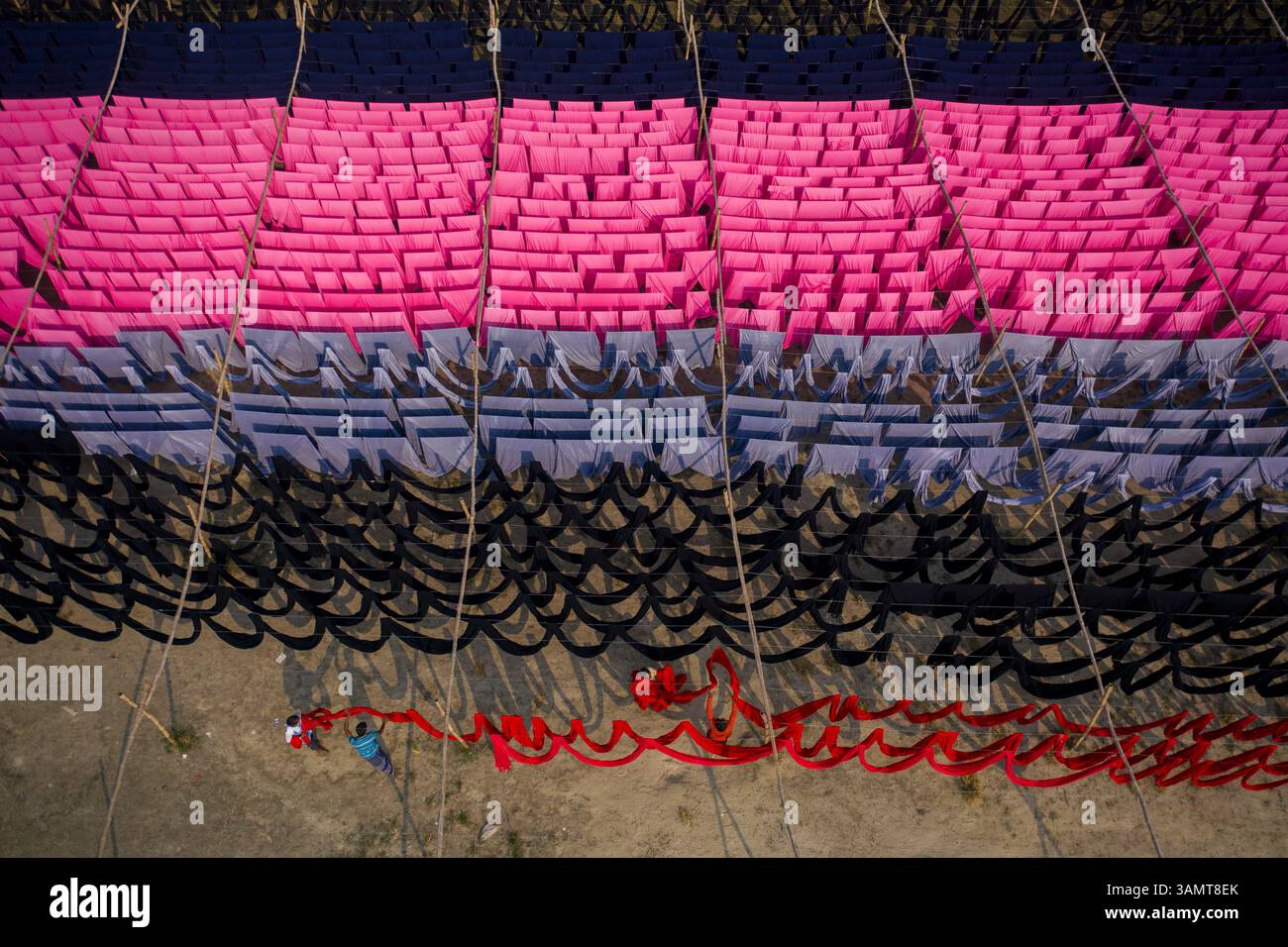 Veduta aerea di lavoratori che pendono migliaia di metri di diversi tessuti colorati per magliette da asciugare a Narayanganj, Dhaka, Bangladesh. Foto Stock