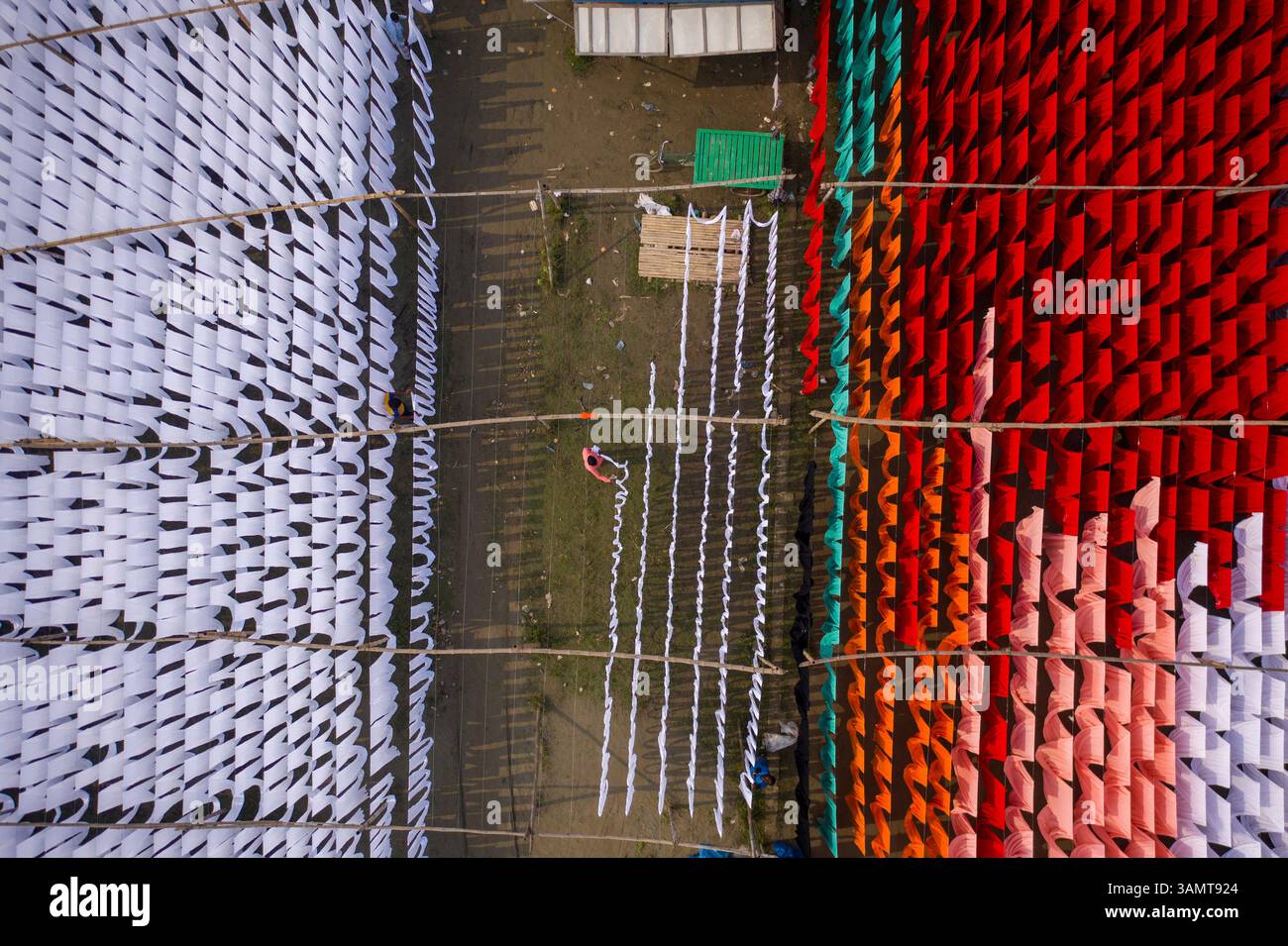 Veduta aerea di lavoratori che pendono migliaia di metri di diversi tessuti colorati per magliette da asciugare a Narayanganj, Dhaka, Bangladesh. Foto Stock