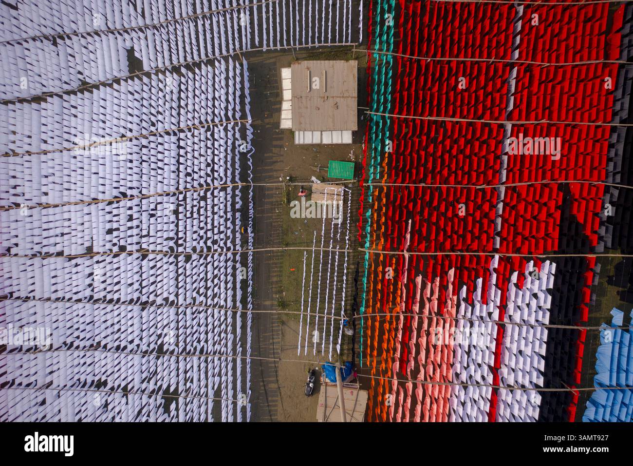 Veduta aerea di lavoratori che pendono migliaia di metri di diversi tessuti colorati per magliette da asciugare a Narayanganj, Dhaka, Bangladesh. Foto Stock