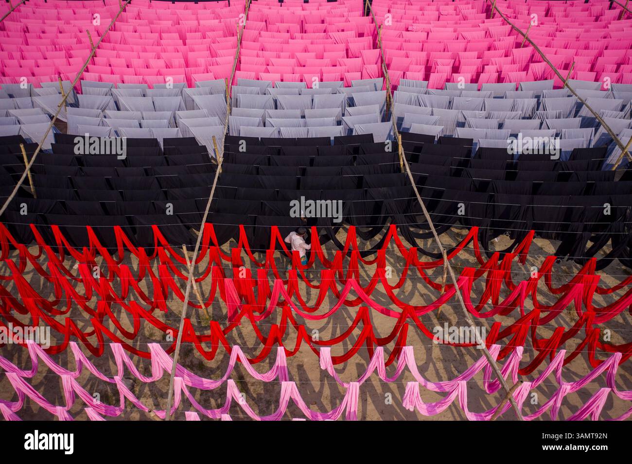 Veduta aerea di lavoratori che pendono migliaia di metri di diversi tessuti colorati per magliette da asciugare a Narayanganj, Dhaka, Bangladesh. Foto Stock