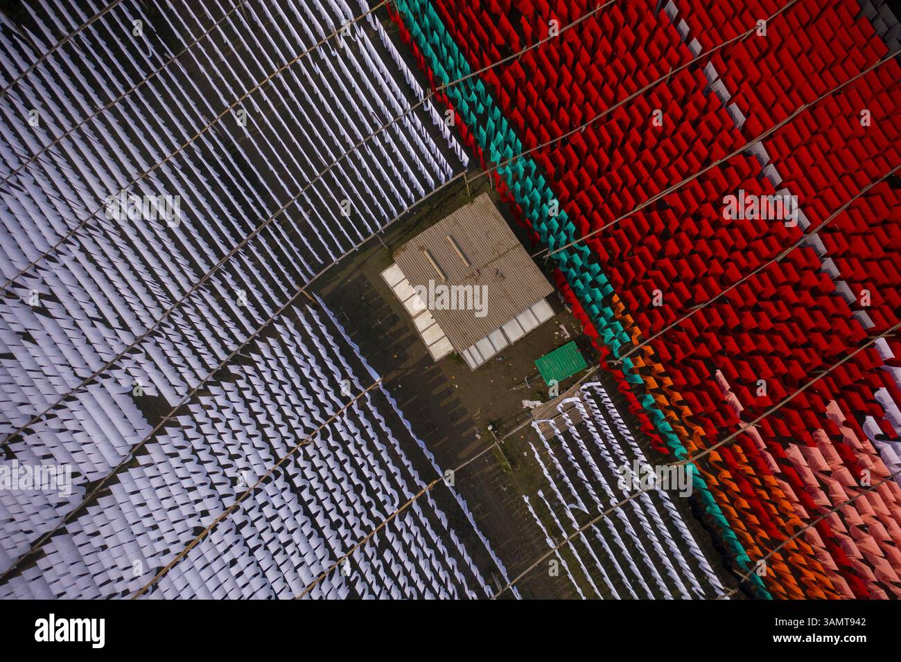 Veduta aerea di lavoratori che pendono migliaia di metri di diversi tessuti colorati per magliette da asciugare a Narayanganj, Dhaka, Bangladesh. Foto Stock