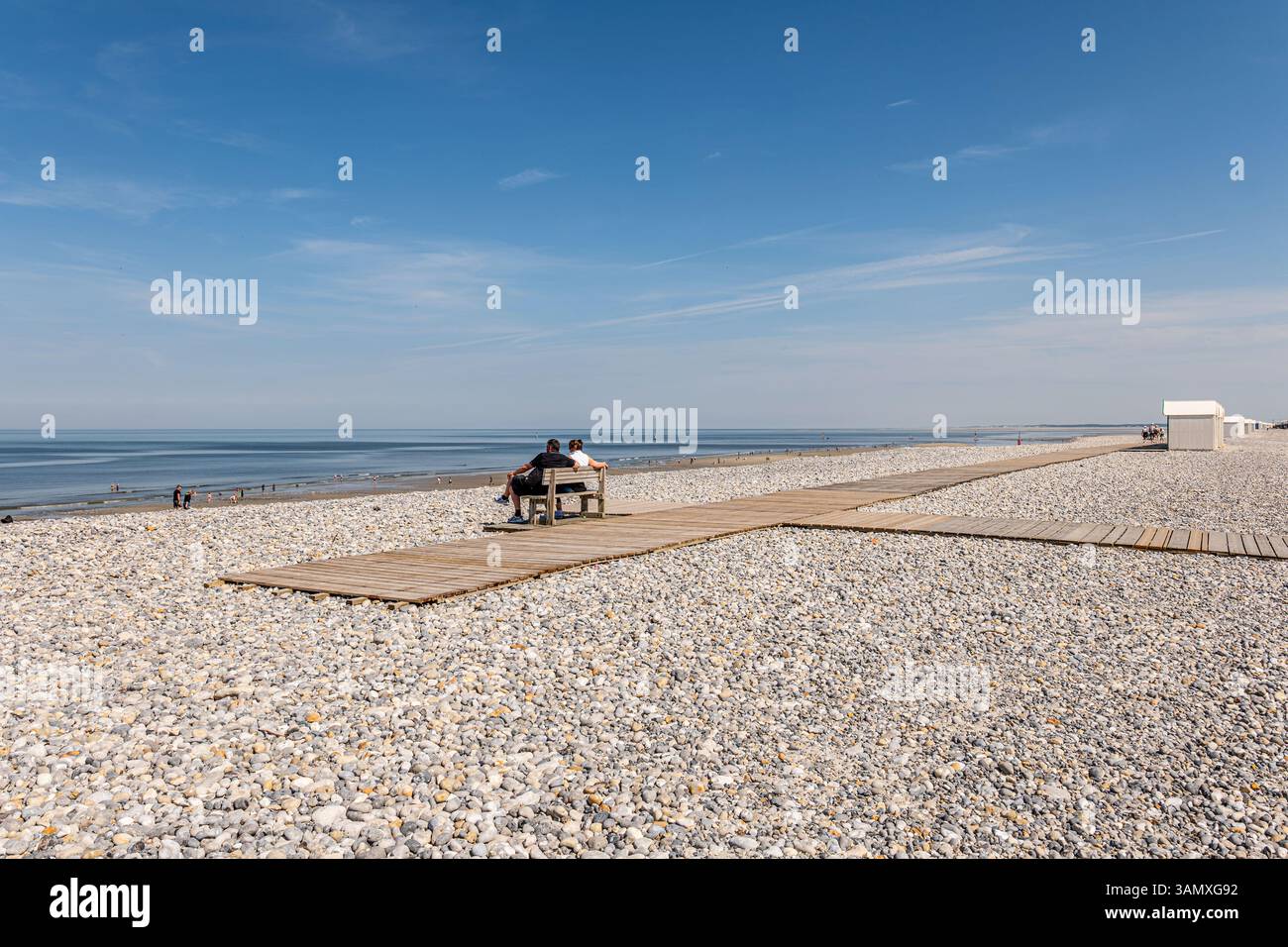 Cayeux-sur-Mer (Francia settentrionale): Rifugi e turisti sulla passerella in legno "chemin des Planches" lungo la spiaggia di ciottoli. Turisti seduti su un essere Foto Stock